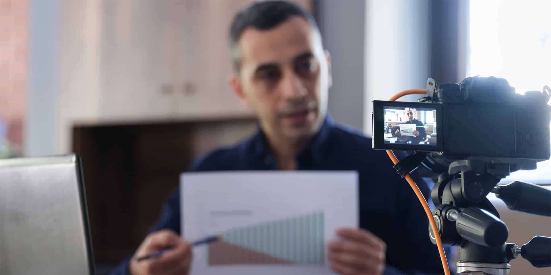 Finfluencer man recording a video while pointing at a chart