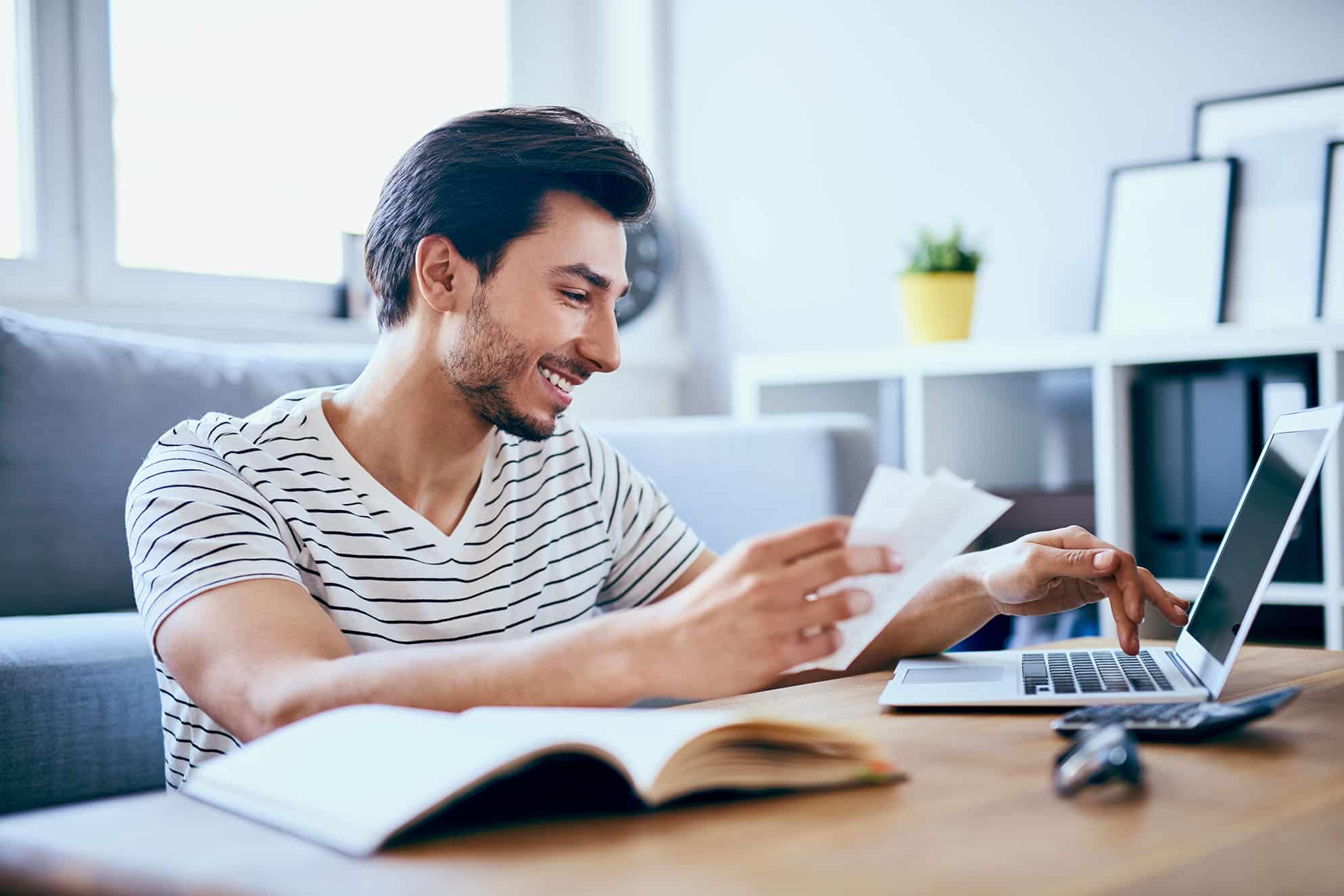 man smiling while checking his investments on laptop