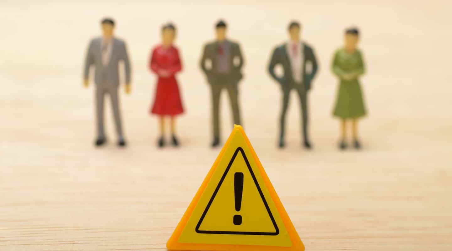 A yellow warning sign in front of a blurred group of people
